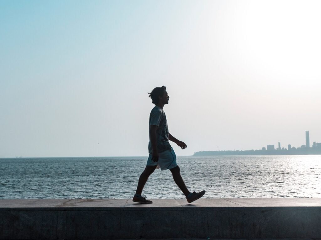 Persona caminando por la playa en verano reflexionando, representando la prevención de recaídas en adicciones durante las vacaciones